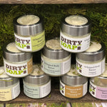 Containers of whipped body butter displayed on a shelf with mossy greenery.