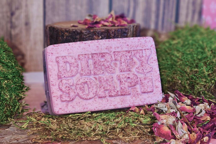 Handmade bar soap labeled 'The New Pink Bar Soap' surrounded by dried flowers and moss.