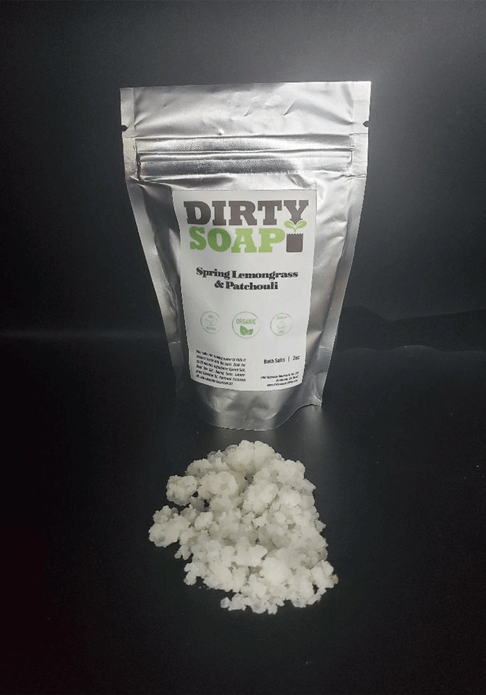 A package of "Dirty Soap" in Spring Lemongrass & Patchouli Bath Salts with its contents spilled in front.