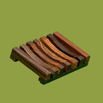 Dirty Soap's eco-friendly wooden soap dish set on a green background.