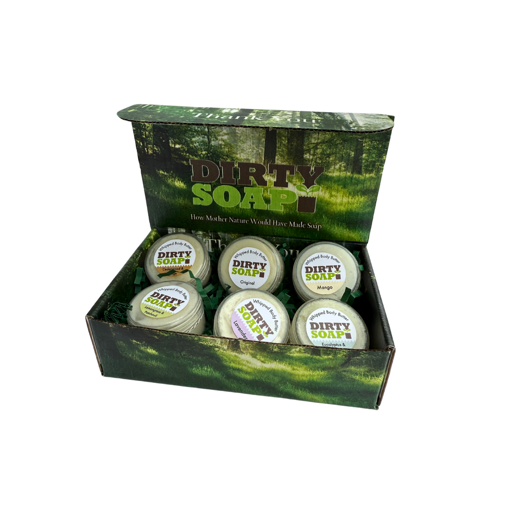 An open "Whipped Body Butter Sampler" by Dirty Soap, featuring six assorted round body butters, perfect for skincare enthusiasts, displayed on a white background.