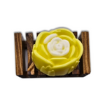 A Yellow Rose Honeysuckle & Jasmine Flower Soap by Dirty Soap Shoppe, designed for stress relief, sits on a small wooden soap dish.