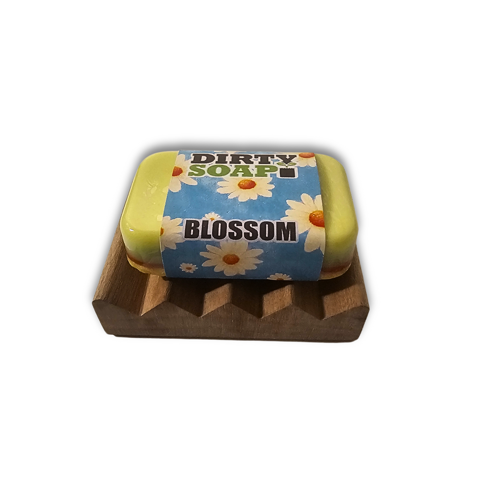 A yellow "Dirty Soap Blossom" bar with a daisy design rests on the Dirty Soap Mini Soap Dish, crafted from natural pine wood with grooves to keep soap from softening.