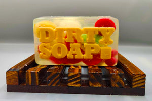 A bar of Christmas Rocks Traditional Bar Soap with the words "dirty soap" embedded inside, presented on a wooden soap dish, infused with Lavender Essential Oil.