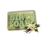 A green Self-Care Bar Soap by Dirty Soap Bubbles, engraved with "DIRTY SOAP" and scented with a calming vanilla lilac fragrance, is shown with vanilla flowers and beans in the lower right corner.