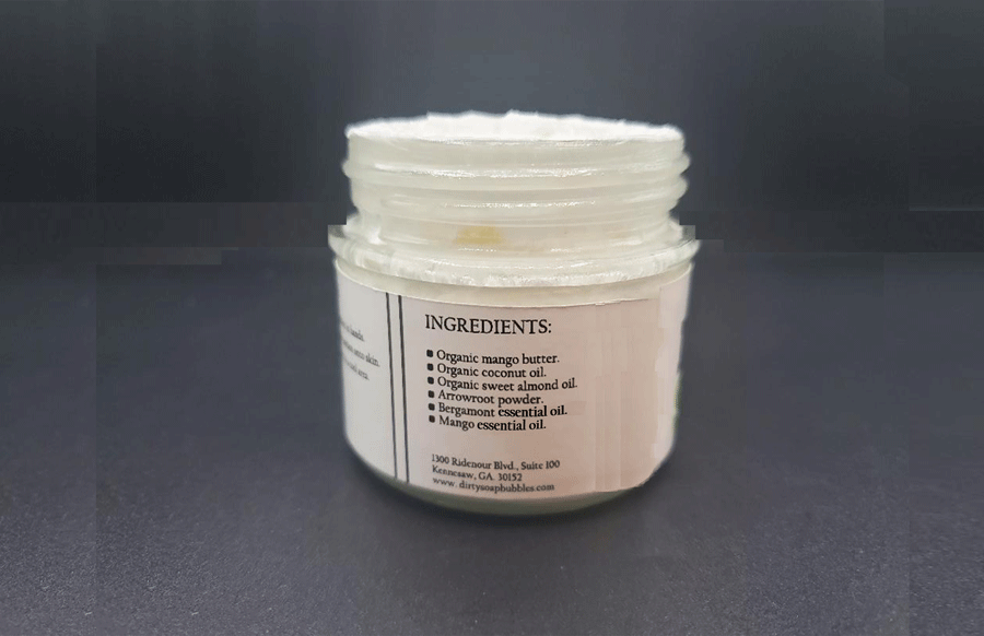 A jar of Dirty Soap Mango Whipped Body Butter with its natural ingredients labeled on the side.