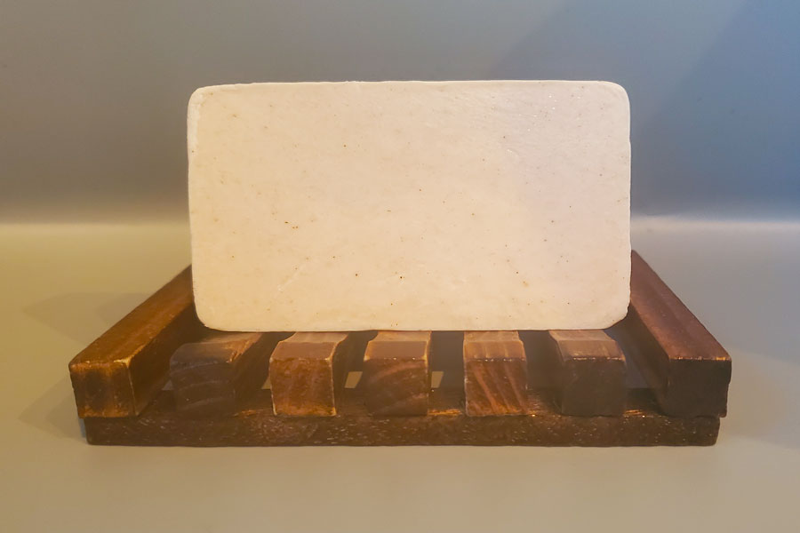 A Mango and Bergamot Bar Soap from Dirty Soap resting on a wooden soap dish.
