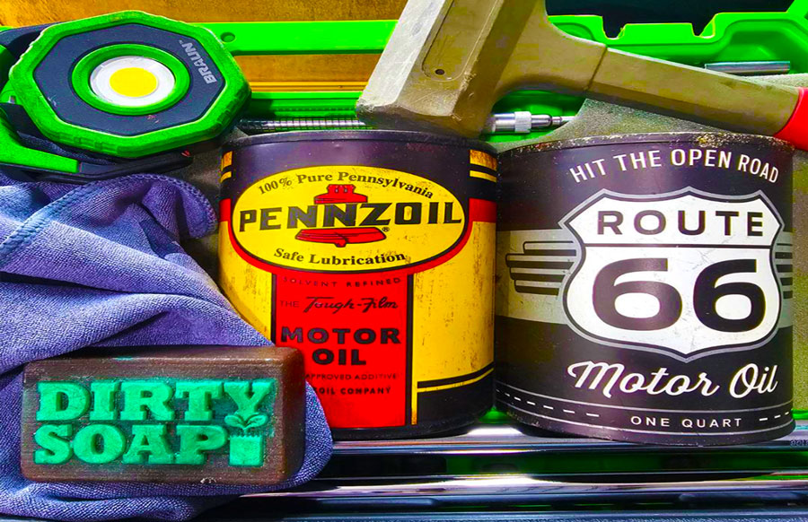 Assorted automotive-themed items including a can of Pennzoil motor oil, a Route 66 motor oil container, a hammer, a level tool, and The Mechanic Bar Soap labeled 'Dirty Soap Bubbles'.