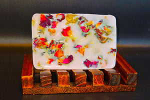 Handmade The New Pink bar soap with embedded flower petals on a Dirty Soap wooden soap dish.