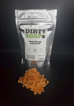 A bag of Dirty Soap brand Burnt Orange & Turmeric Bath Salts, with a spilled sample of the product in front.