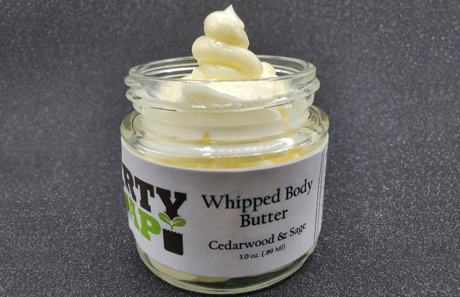 Jar of Cedarwood And Sage Whipped Body Butter with a swirl of organic shea butter on top against a grey background by Dirty Soap Bubbles.