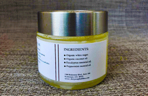 A jar of Eucalyptus And Mint Sugar Scrub by Dirty Soap Bubbles with a label listing ingredients, including organic white sugar and coconut oil, eucalyptus essential oil, and peppermint essential oil.