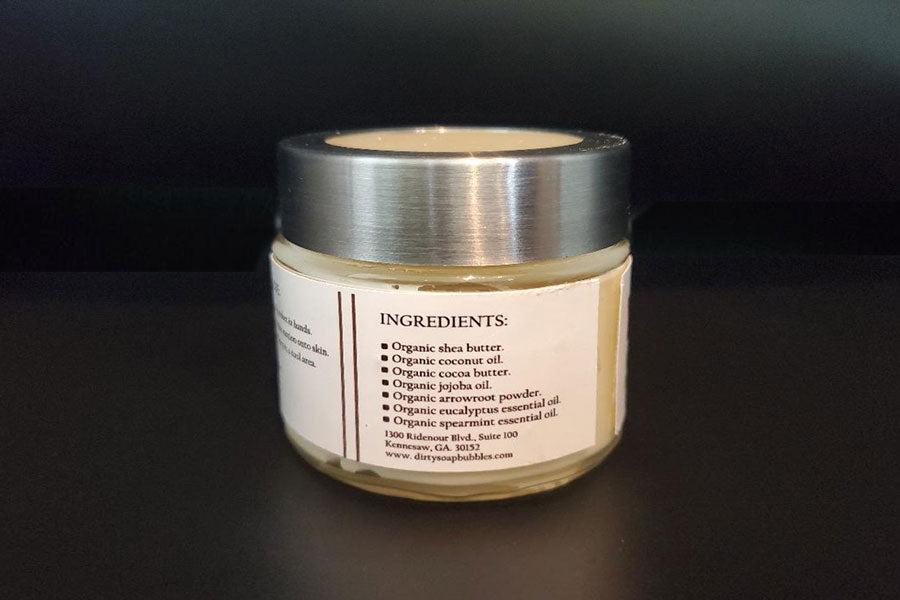 A jar of Eucalyptus and Spearmint Whipped Body Butter made with cocoa butter and shea butter, displaying its natural ingredients on the label by Dirty Soap Bubbles.