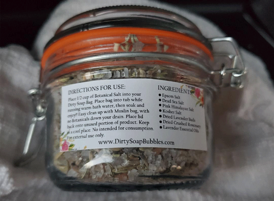 A jar of Lavender Rosemary Botanical Salt with a label containing directions for use and a list of ingredients, including Dead Sea Salt and Lavender Essential Oil from Dirty Soap.