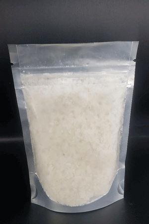 Sealed plastic pouch containing Spring Lemongrass & Patchouli Bath Salts, a white crystalline substance for a relaxing soak by Dirty Soap.