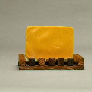 A bar of Dirty Soap Bubbles' Burnt Orange & Turmeric with Safflower Oil Bar Soap displayed on a small wooden pallet.