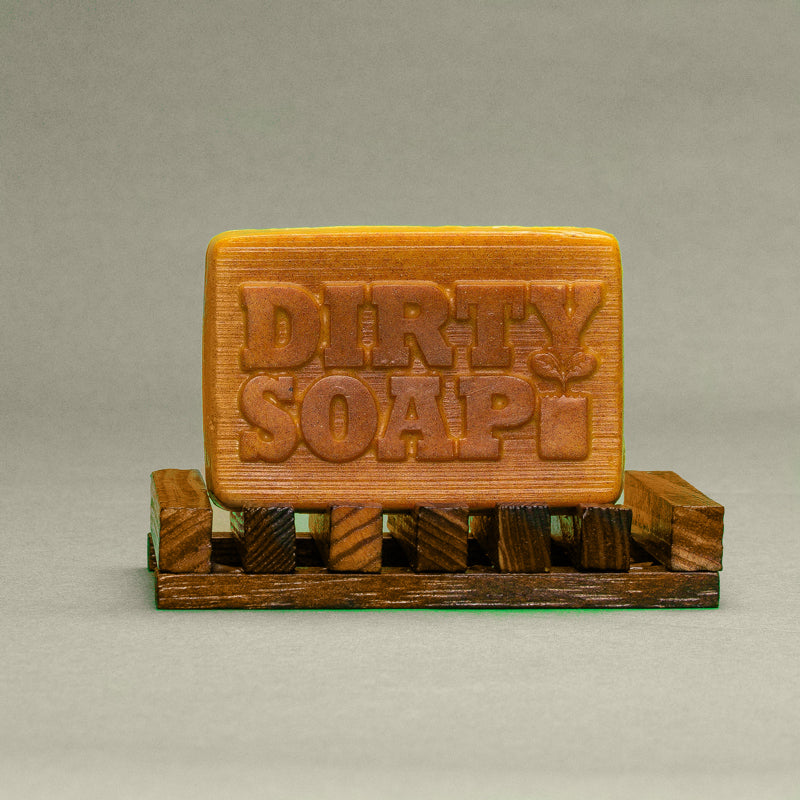 A bar of Burnt Orange & Turmeric with Safflower Oil Bar Soap from Dirty Soap Bubbles, resting on a small wooden pallet.